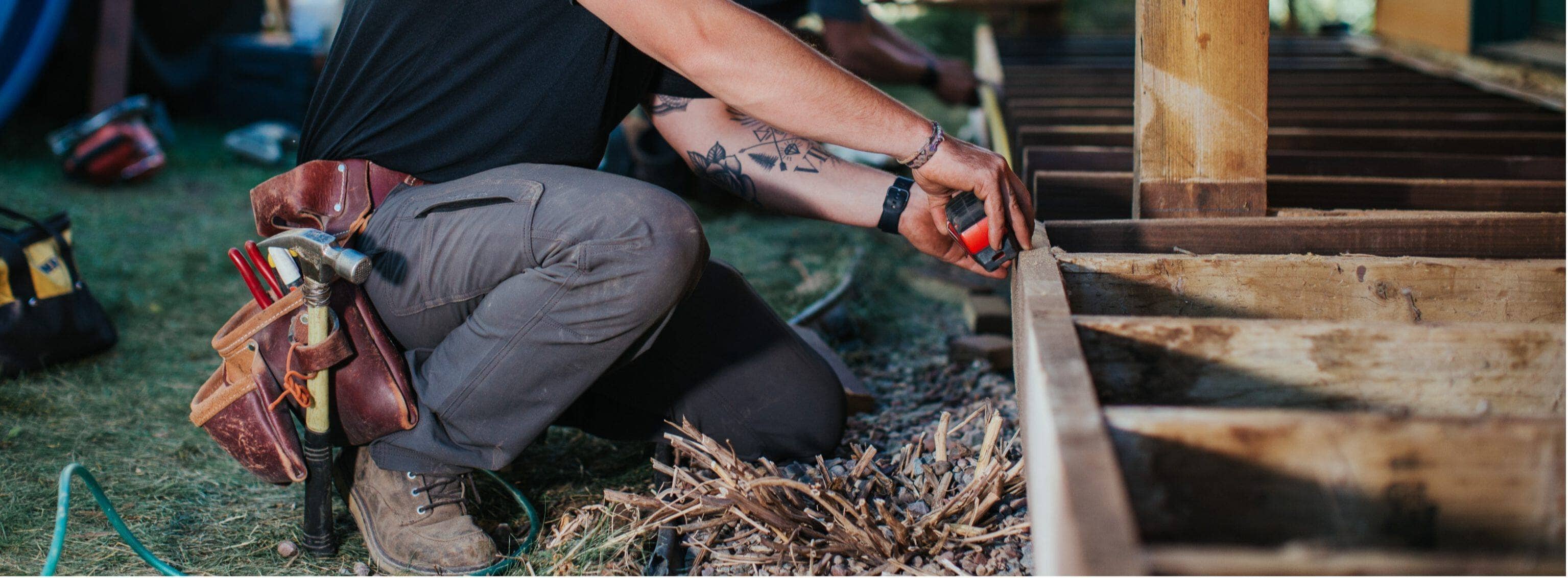 A male tile splitter wearing gray Truewerk WerkPants kneels and works at a jobsite.