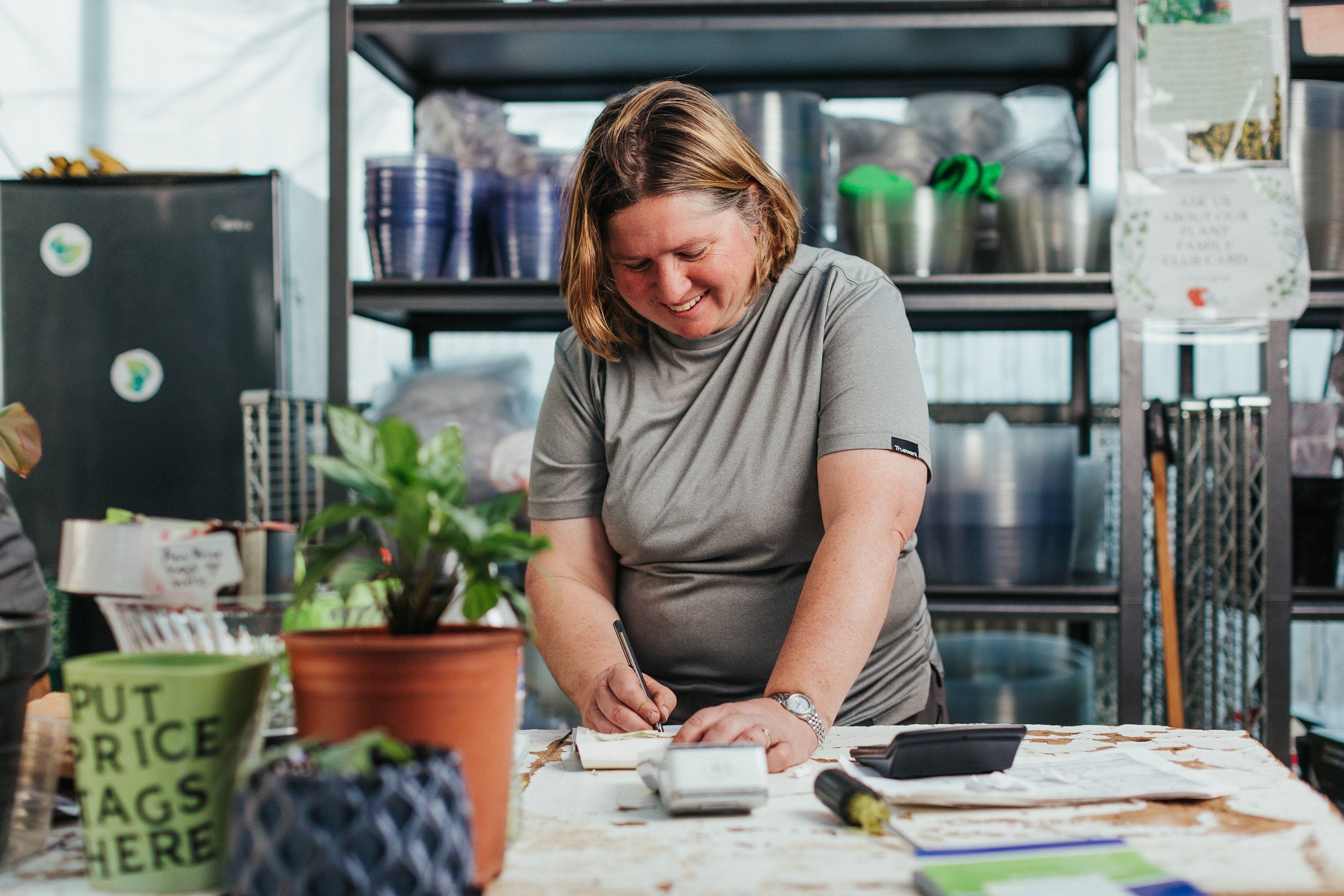 A technician at Little Eden wears a Truewerk workwear shirt as she works at a work table.
