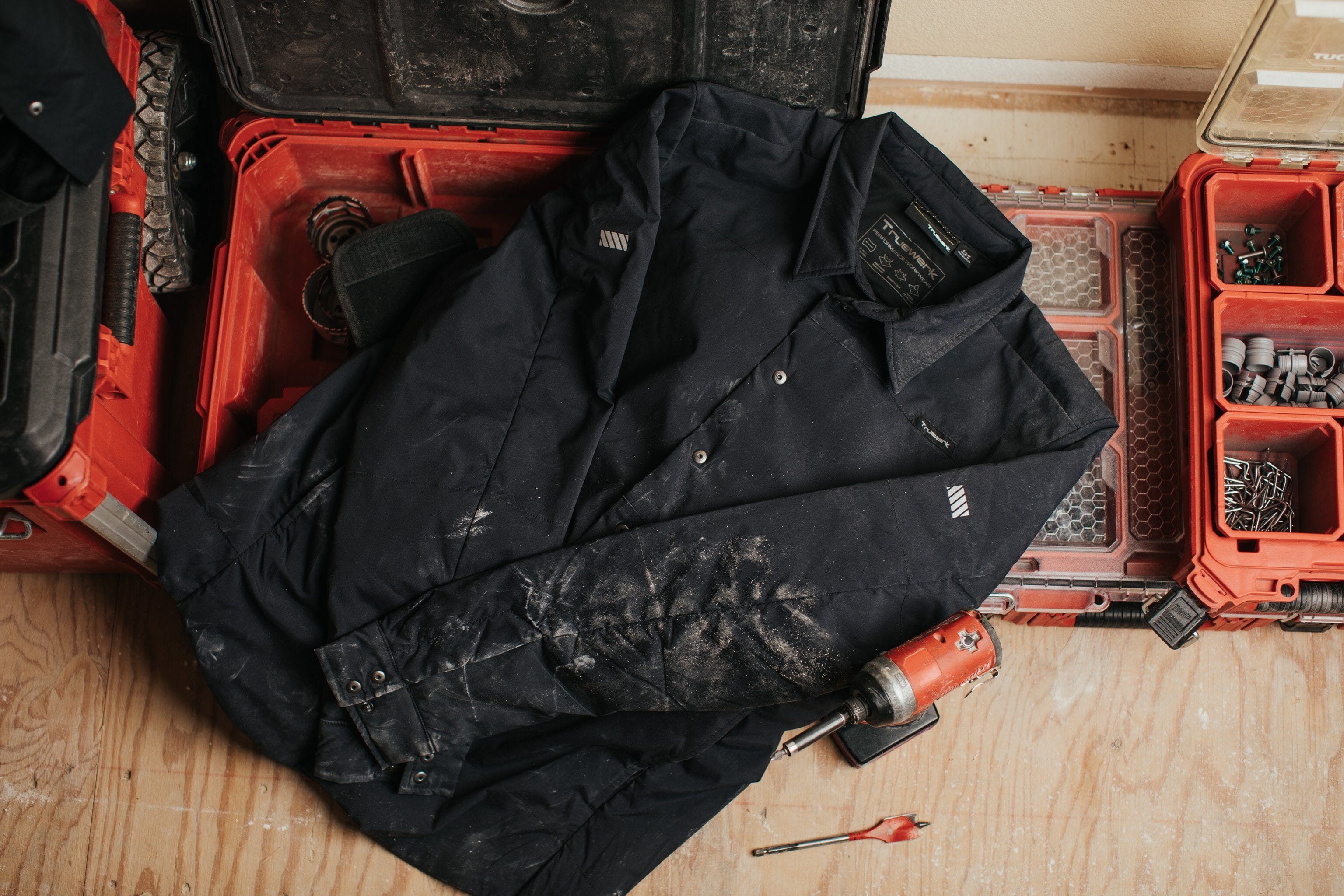 A black Truewerk workwear jacket, with dirt on it from the job site.
