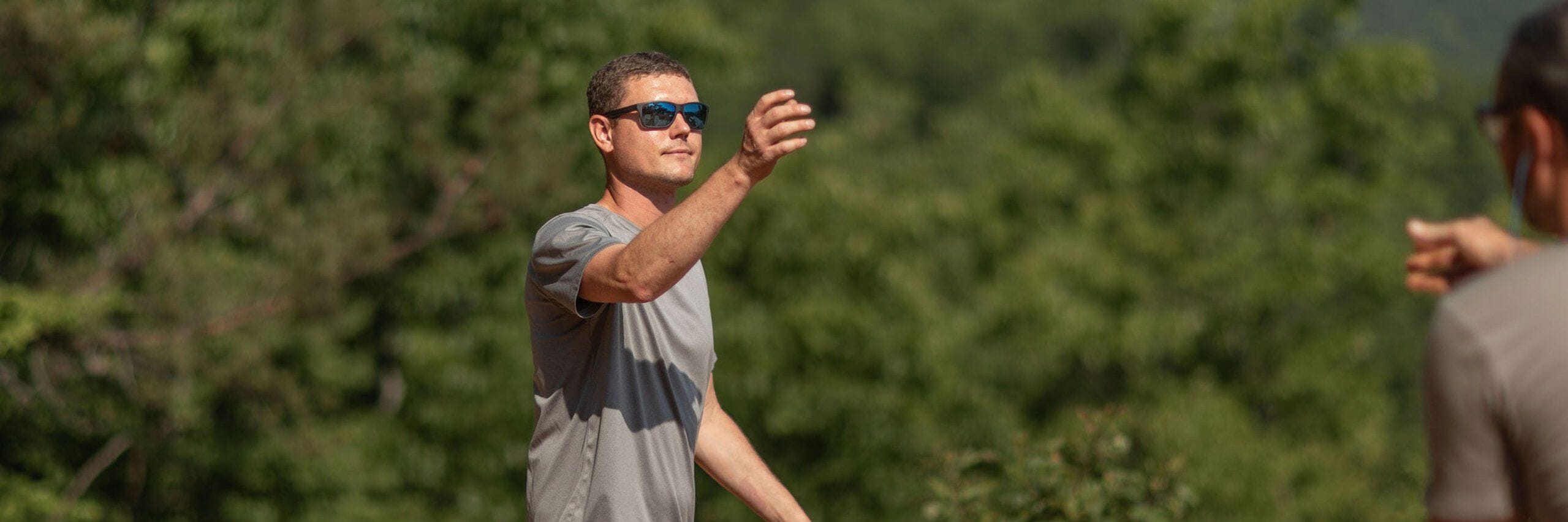 A male trade professional wearing sunglasses and a Truewerk shirt prepares to catch a measuring tape being thrown to him.