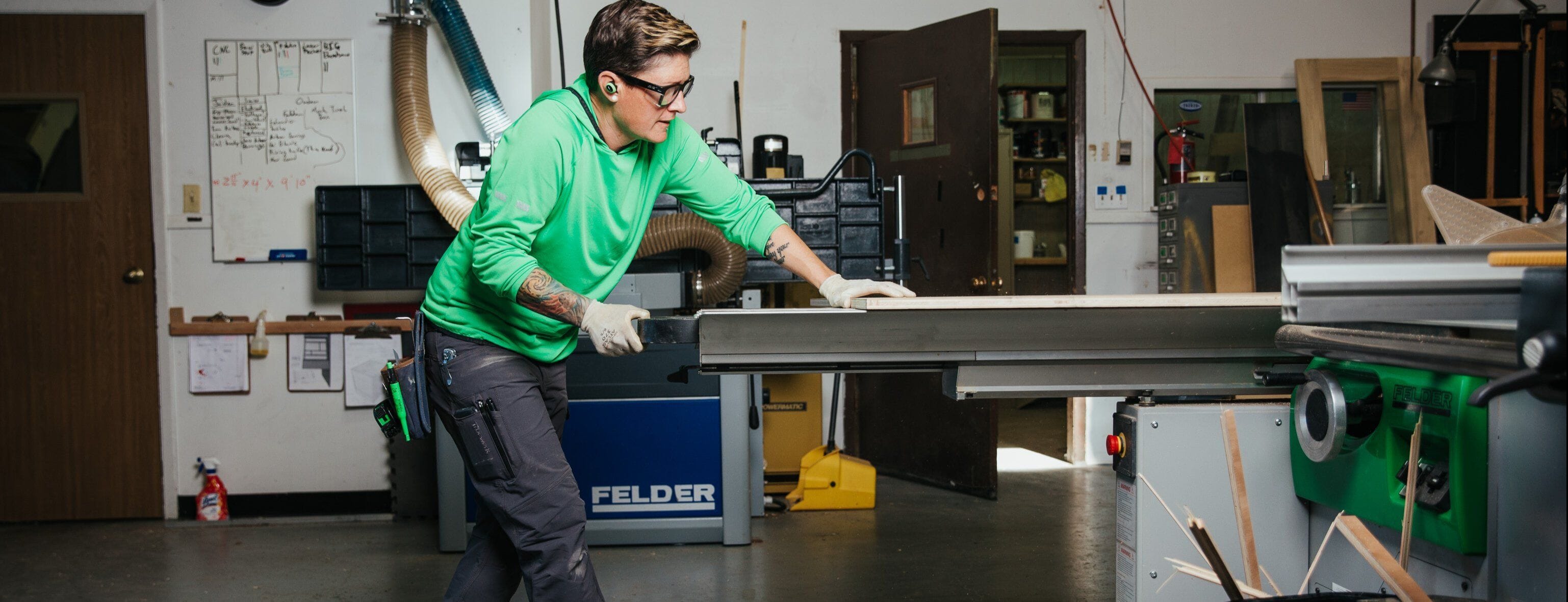 A trade professional wearing Truewerk WerkPants, a T.5 WerkHoody, and earplugs adjusts a machine.